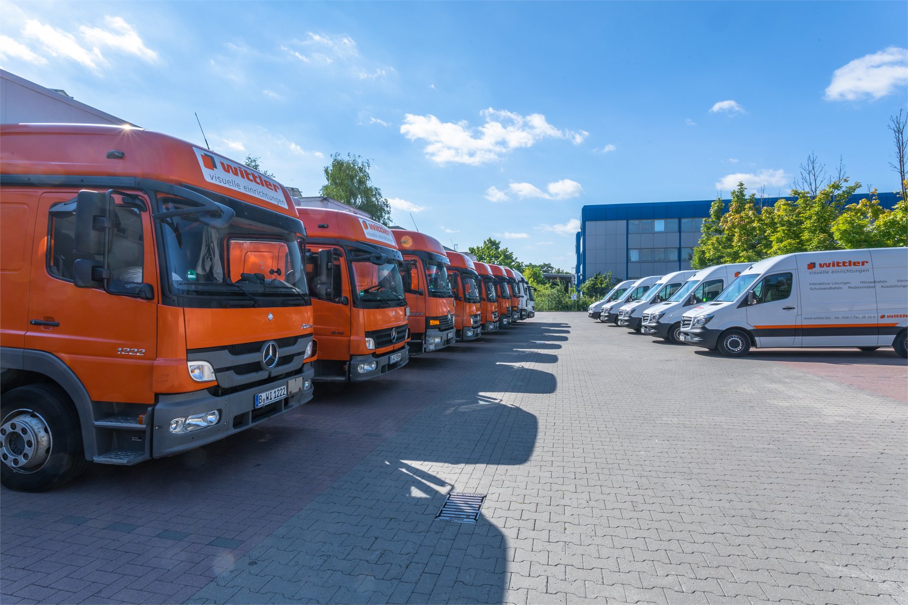Großer Wittler-Fuhrpark mit orangefarbenen LKW und weißen Montagefahrzeugen